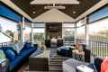 Stylish sunroom with dark wicker furniture, blue cushions, and a striped rug sets the stage for outdoor living in Delaware County, PA. Large windows offer scenic views and ample natural light. A small table with decorative items and plants completes the cozy space.