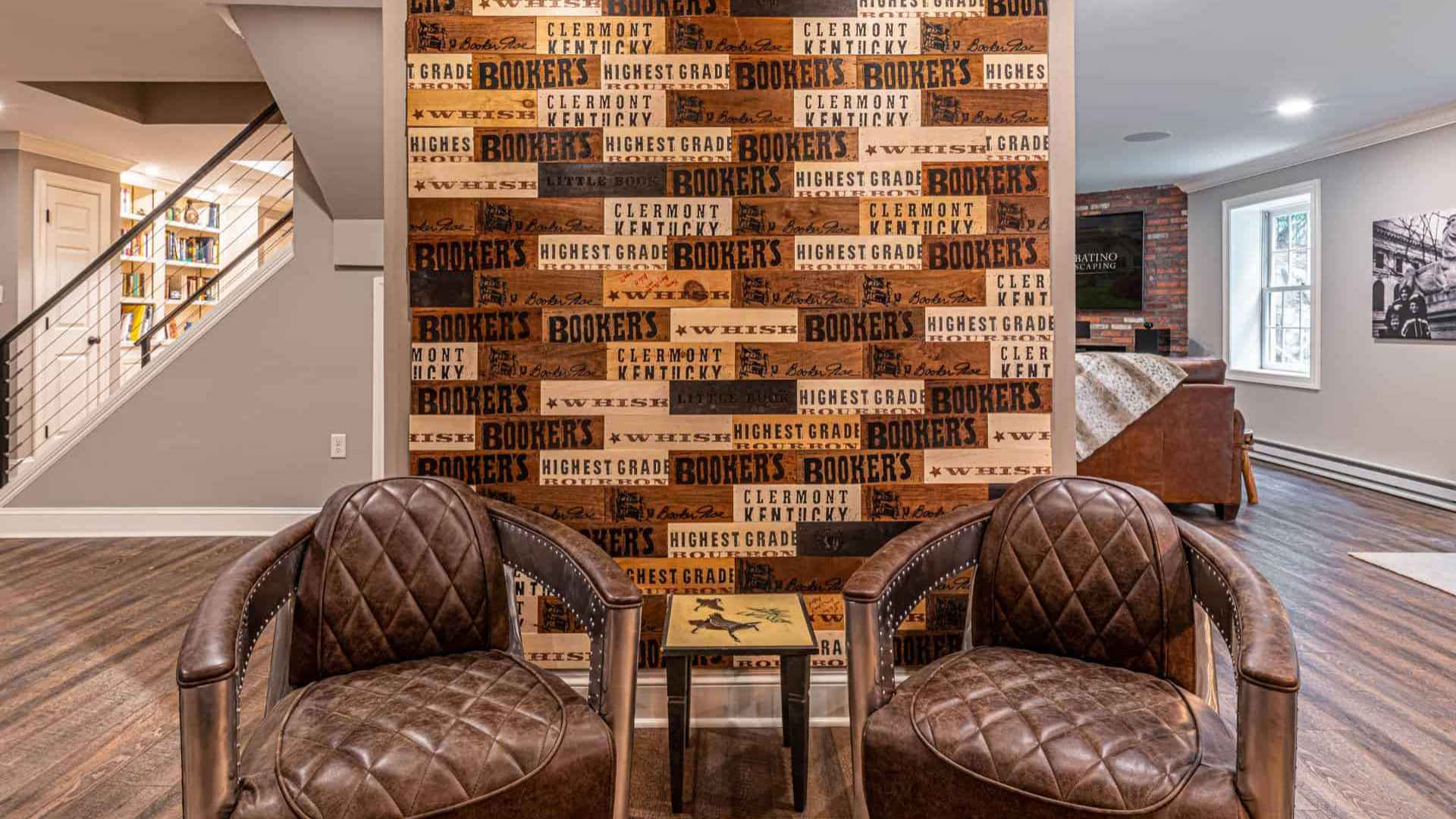 Two brown leather armchairs face a wall adorned with a collage of wooden boards featuring text like 