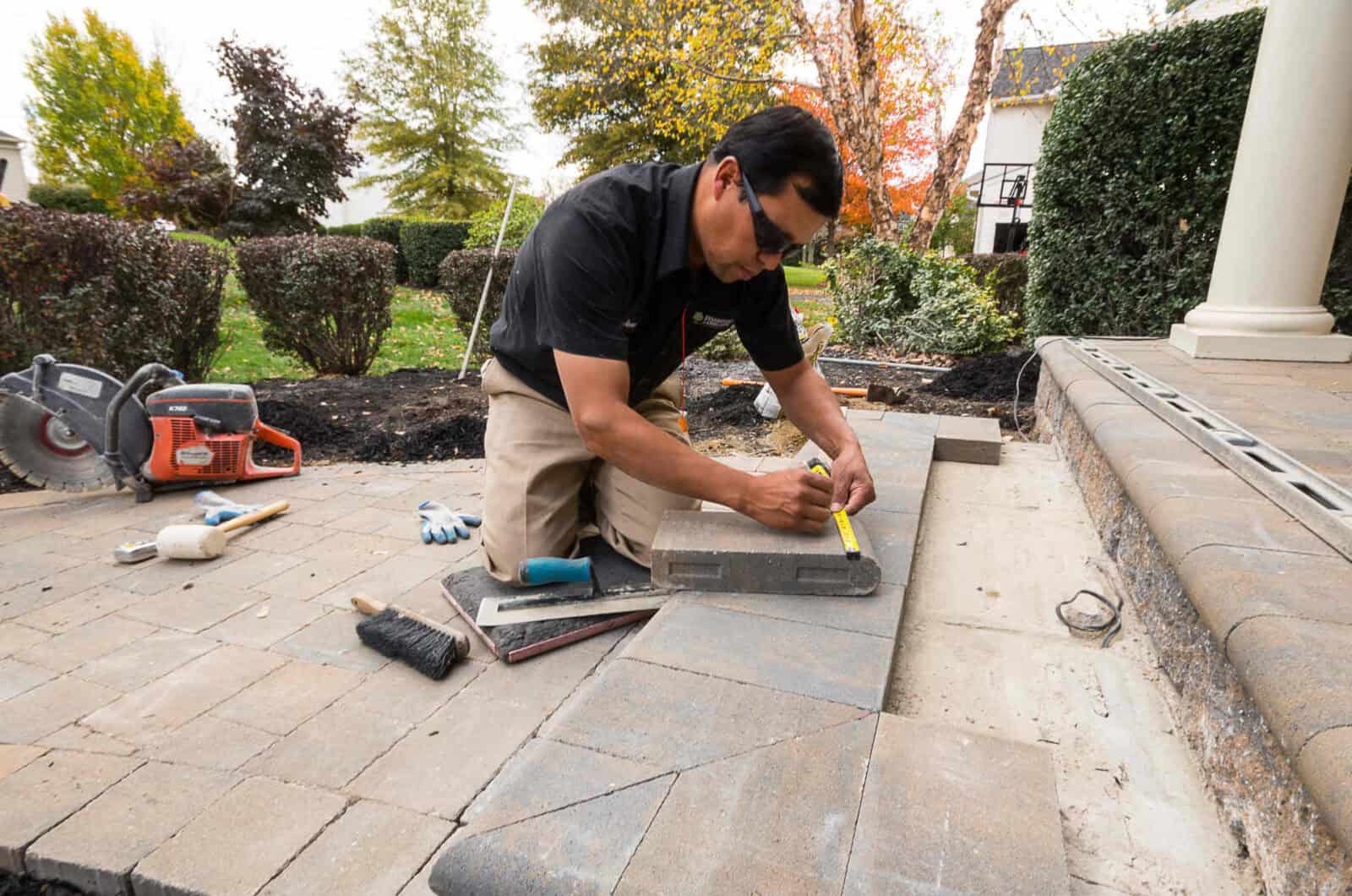 Measuring paver steps for precise installation at a DiSabatino Landscaping project in New Castle County, DE, ensuring perfect results