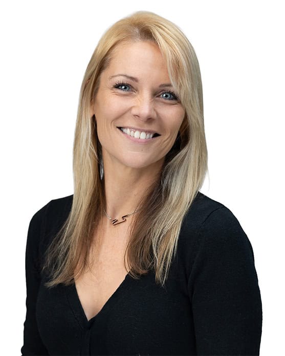 Smiling woman with long, straight blonde hair wearing a black top and a necklace, posed against a plain white background.