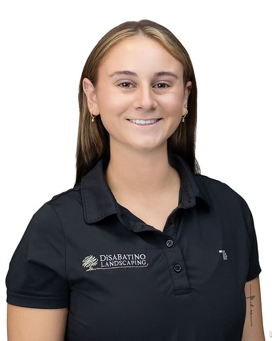 A person with straight, light brown hair and a friendly smile wears a black polo shirt with the DiSabatino Landscaping logo, standing against a white background.